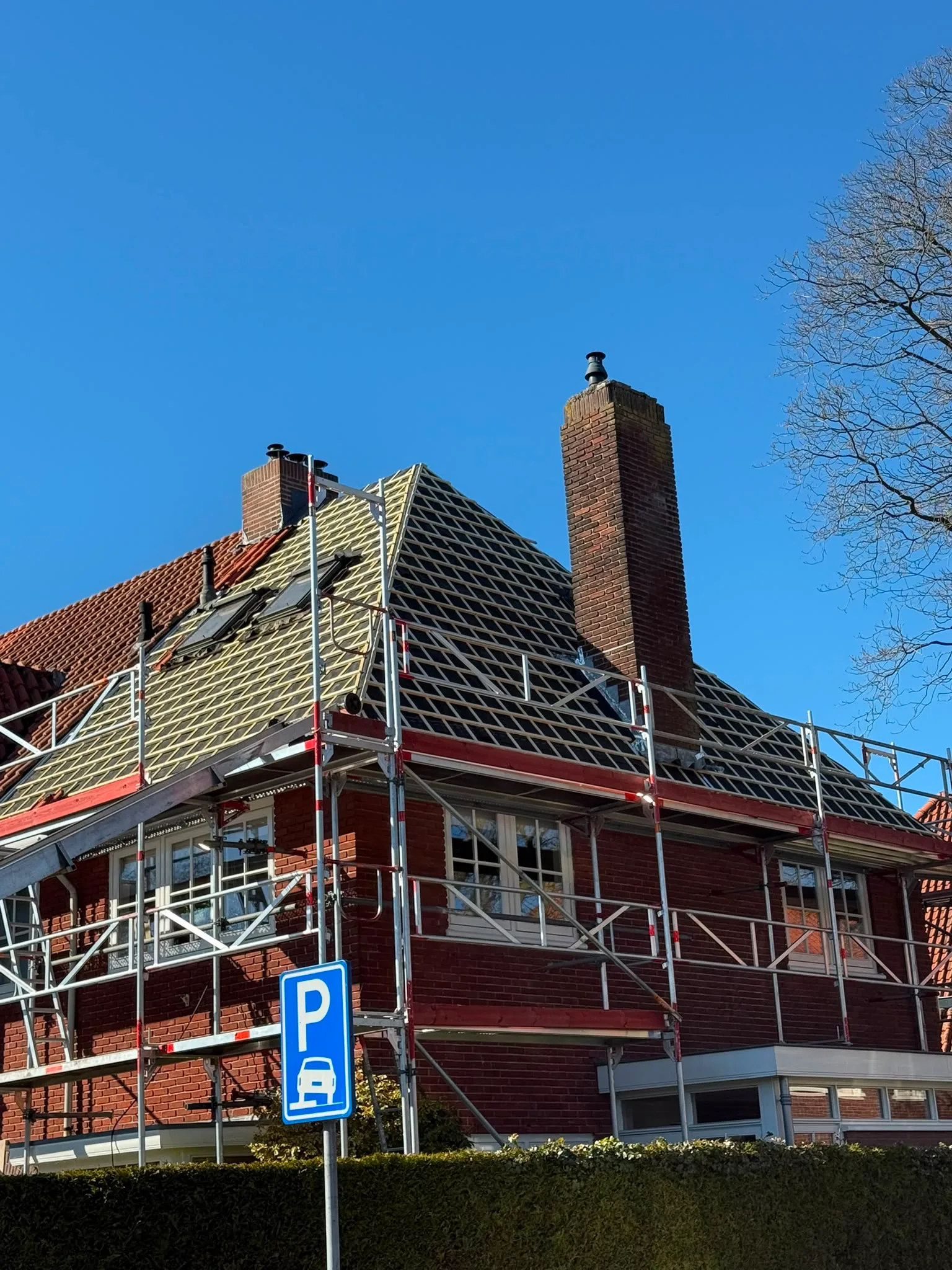 Dakrenovatie met gele dakpannen en steigers