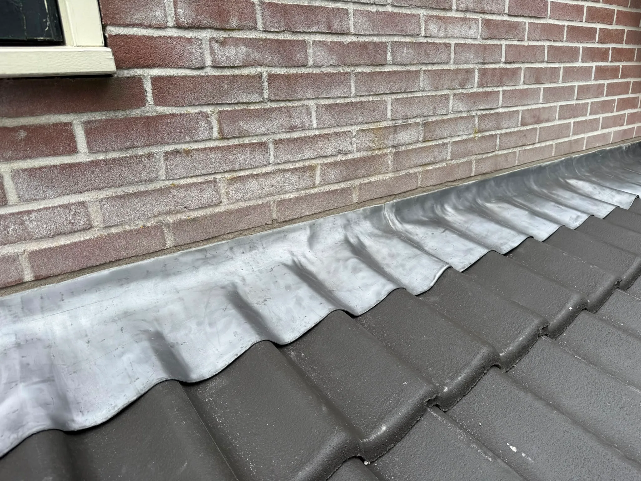 Witte dakgoot tegen bakstenen muur