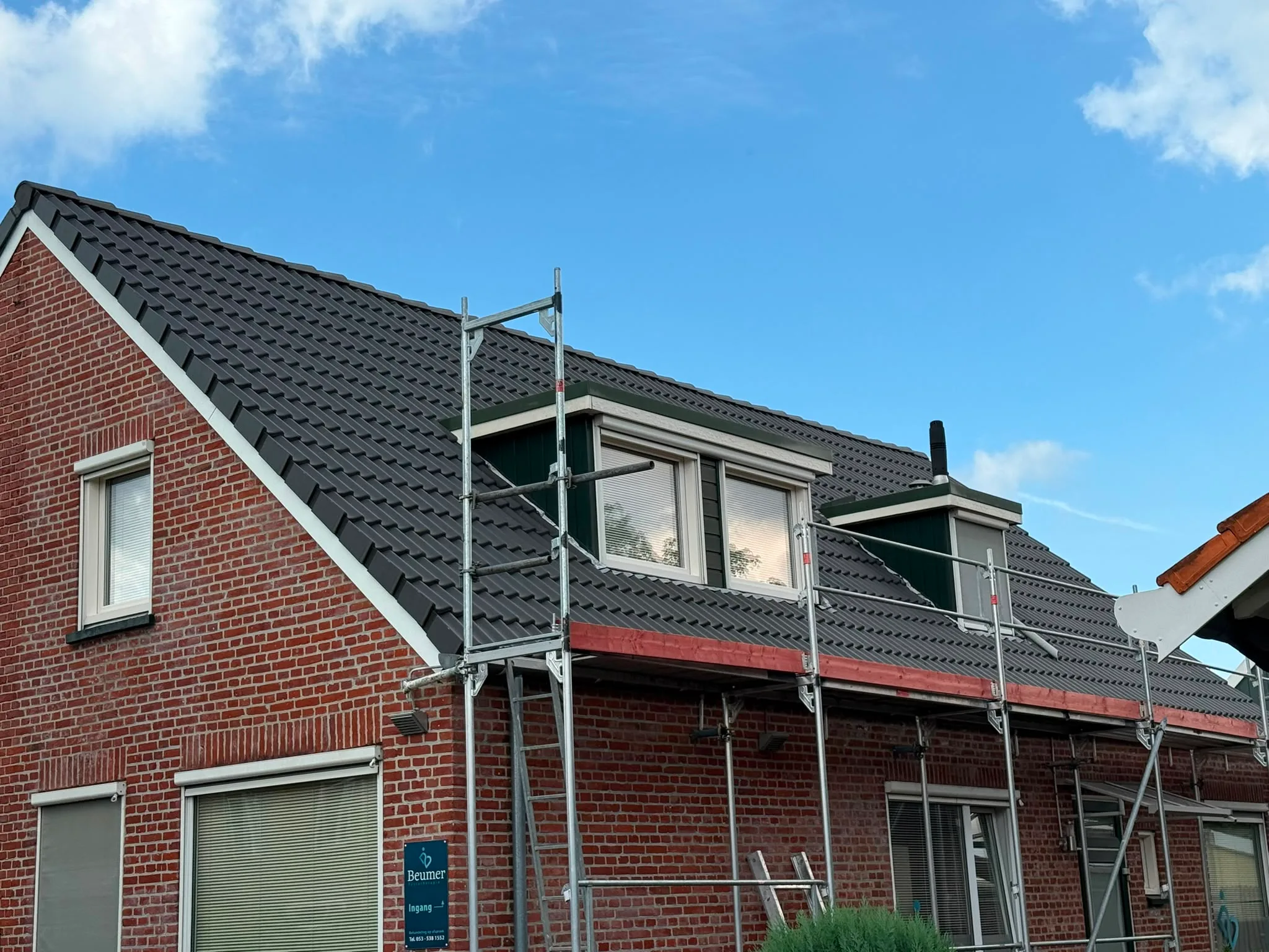Dakrenovatie met steigers op bakstenen woning