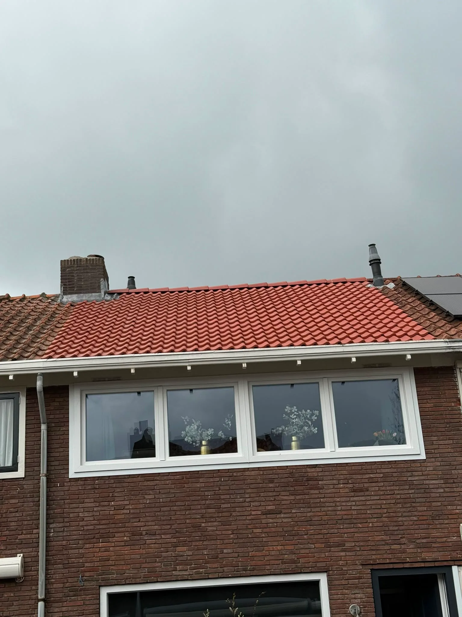 Gerenoveerd dak met rode dakpannen op woning