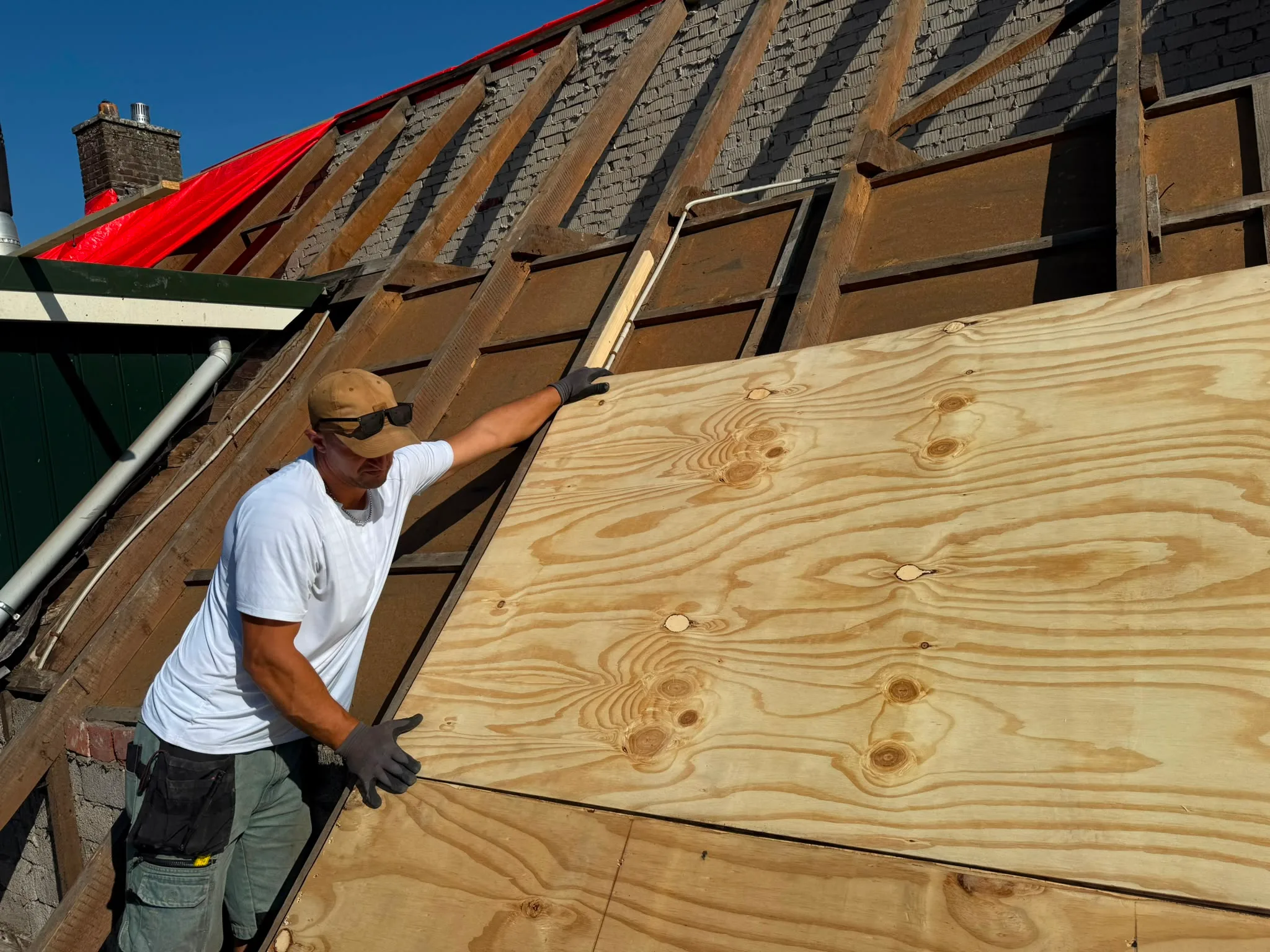 Dakrenovatie met arbeider en houten afscherming